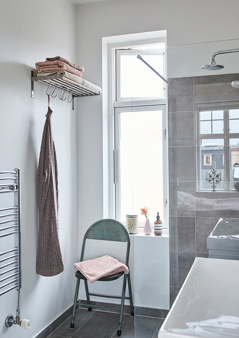 Klappstuhl und Garderobe im Badezimmer mit Fenster