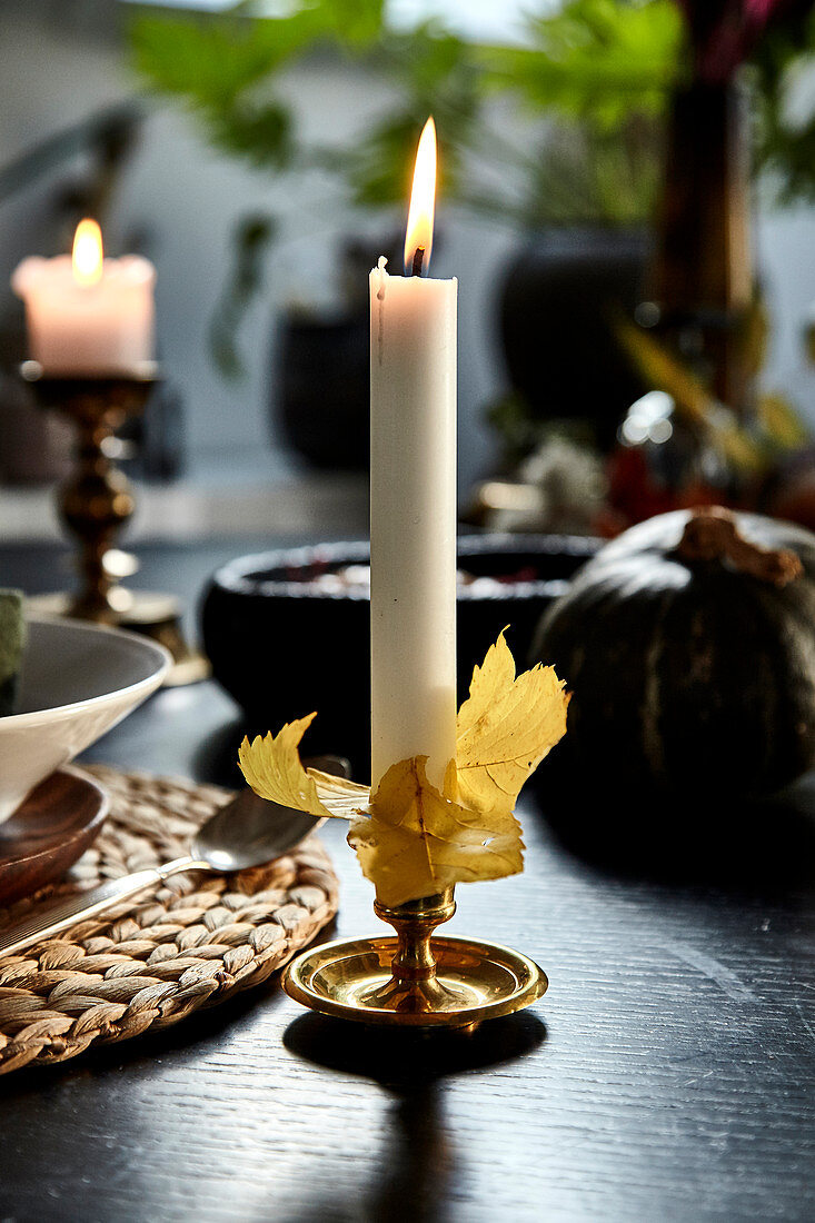 Kerze mit Herbstlaub dekoriert