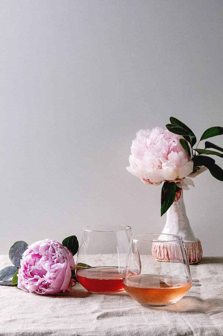 Zweierlei Rosewein in Gläsern auf Tisch dekoriert mit Pfingstrosen
