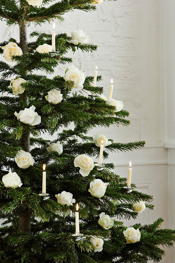 Christmas tree decorated with white roses and white candles