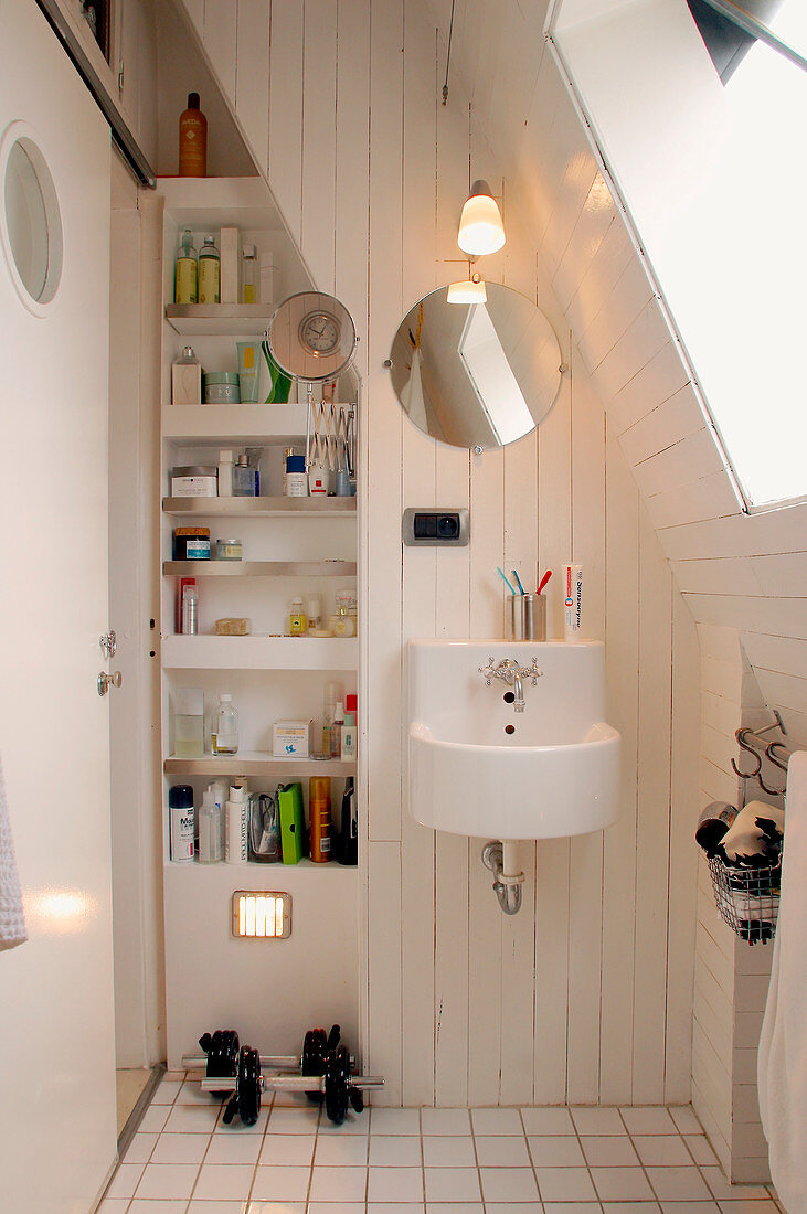 Small bathroom under the slope with skylight and built-in shelving