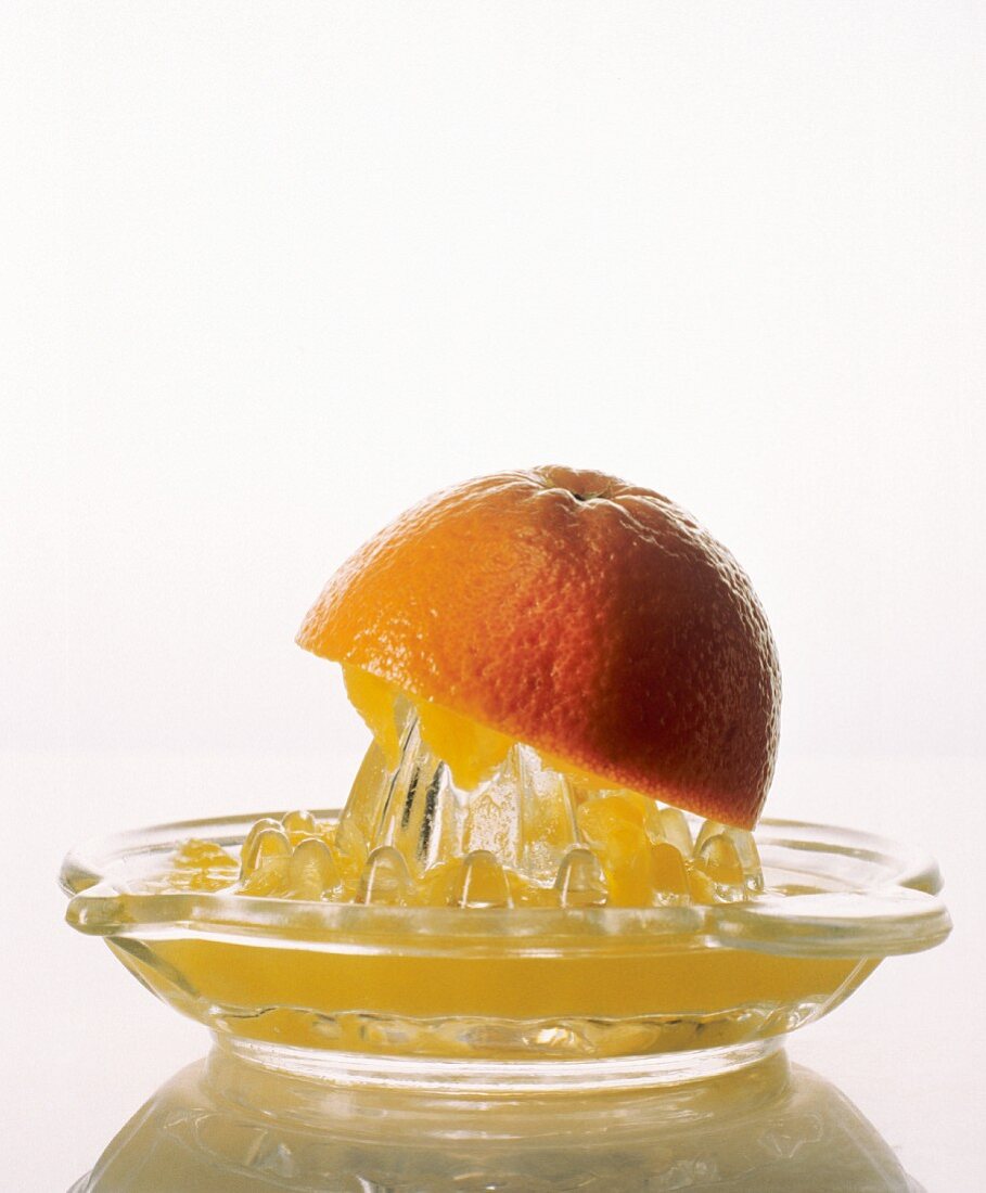 Eine Orangenhälfte auf Zitruspresse mit Orangensaft