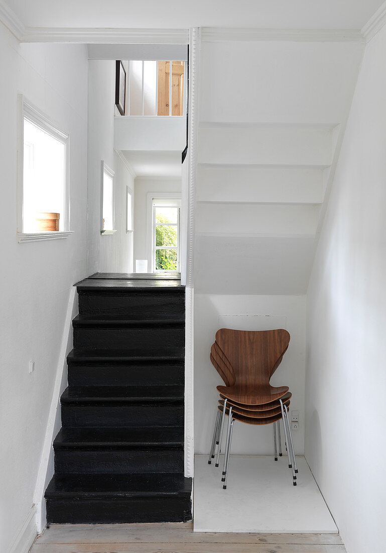 Stack of designer chairs under the stairs with black steps