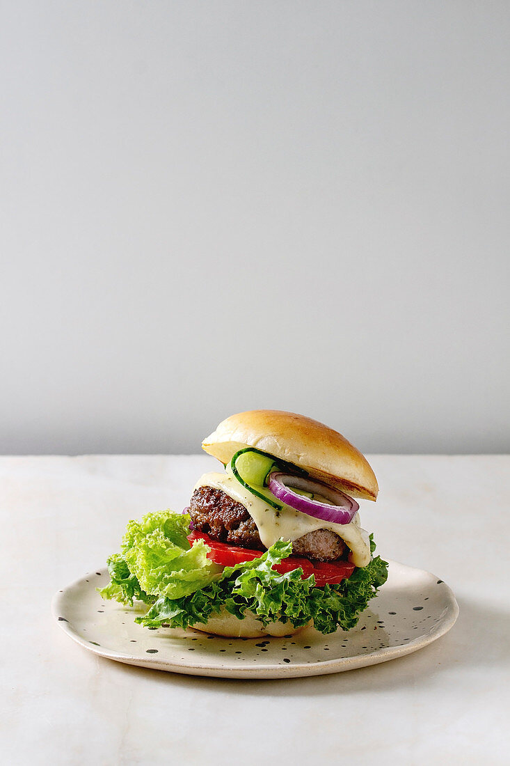 Selbstgemachter Cheeseburger mit Tomate und Salat auf Teller