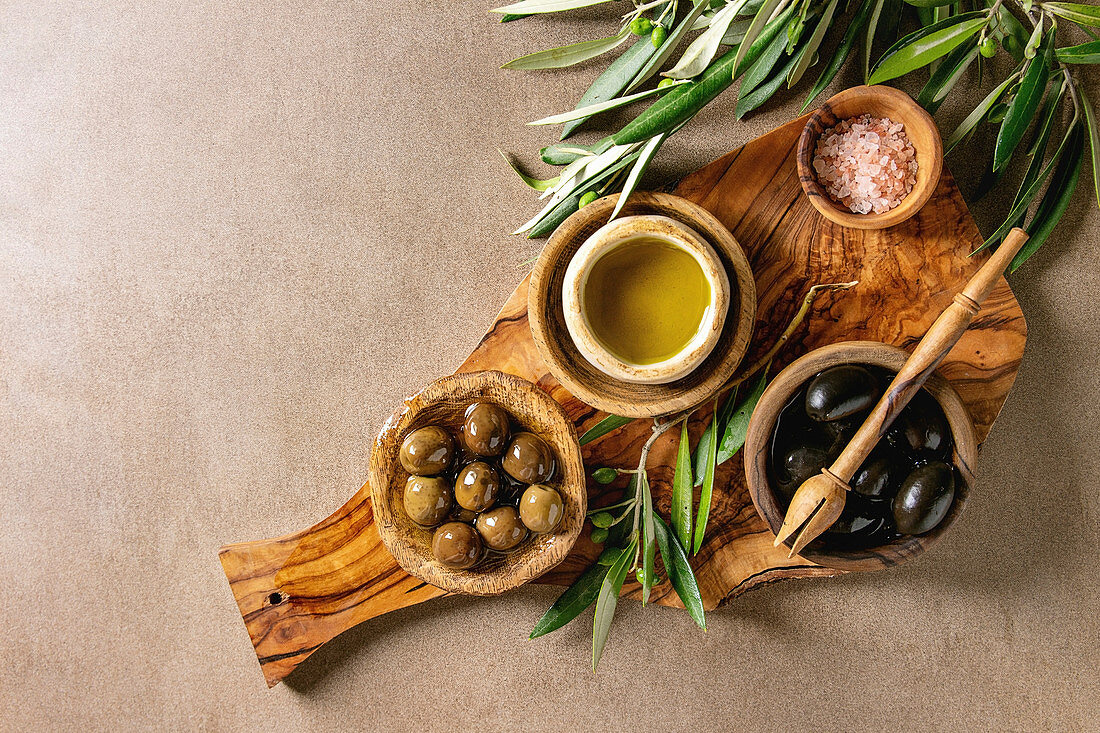 Verschiedene eingelegte Oliven serviert mit Öl und Salz auf Holzbrett