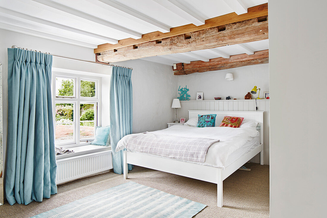 Helles Schlafzimmer mit Holzbalken und blauen Akzenten in renoviertem Bauernhaus