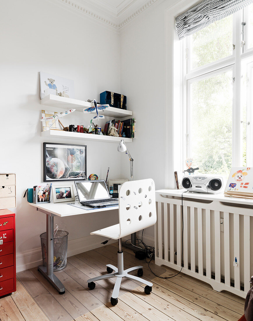 A swivel chair at a desk in a teenager's bedroom with a wooden floor