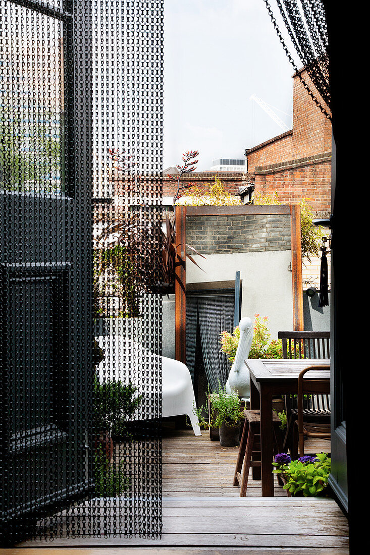 Schwarze Metallkette als Türvorhang, Blick auf Innenhof mit Terrassenmöbeln
