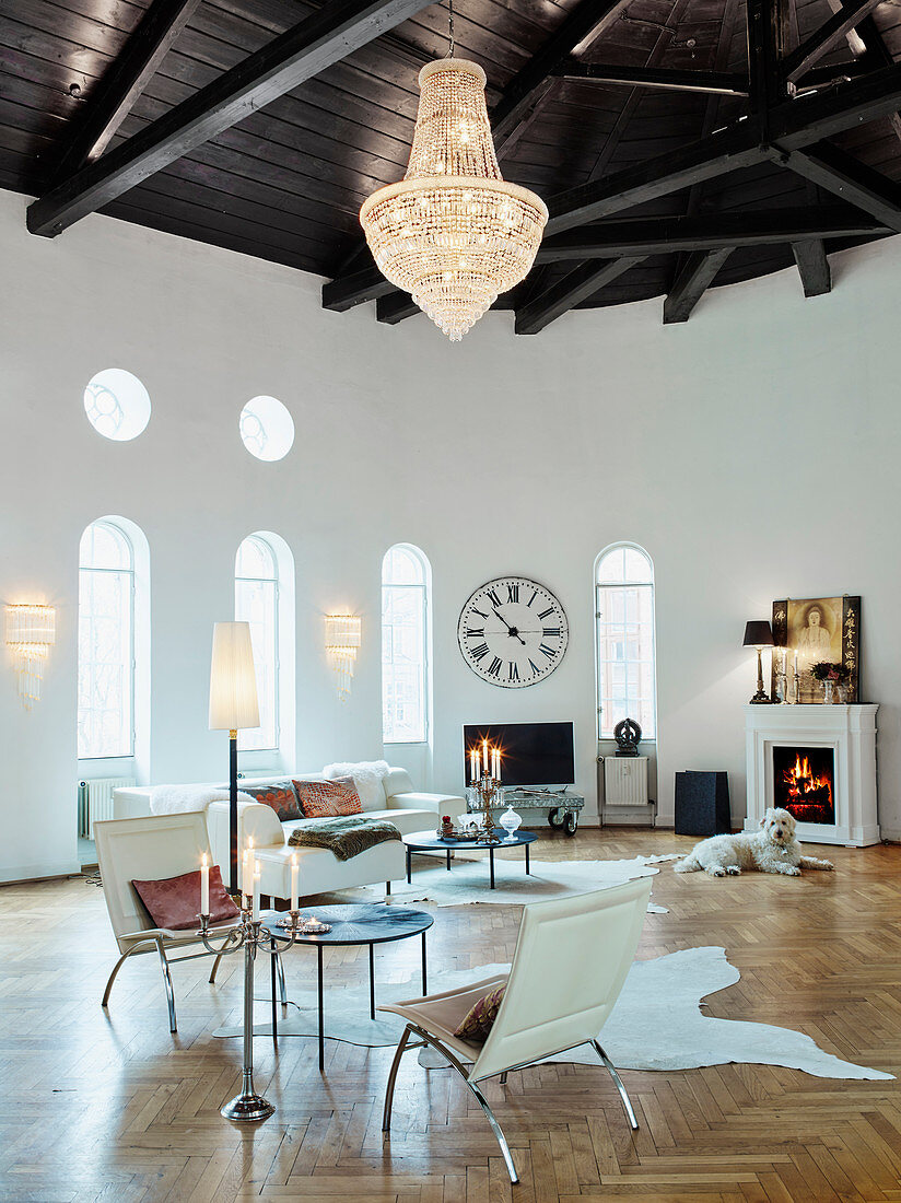 A spacious living room with a curved wall, white seating furniture and a dog in front of a fireplace