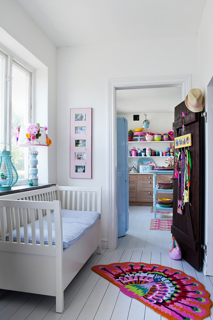 White bench in the hall with white wooden floor and colorful rugs