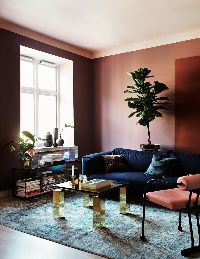 An elegant living room with dusky pink walls and a blue sofa
