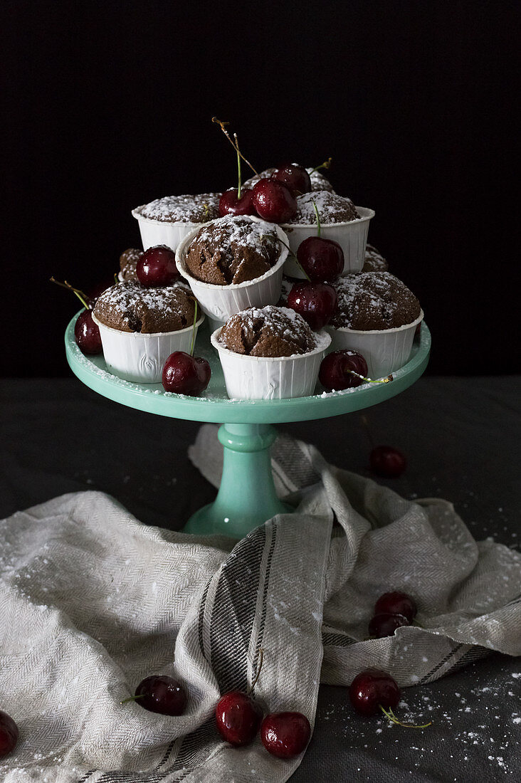 Cupcakes mit Puderzucker und Kirschen auf Kuchenständer