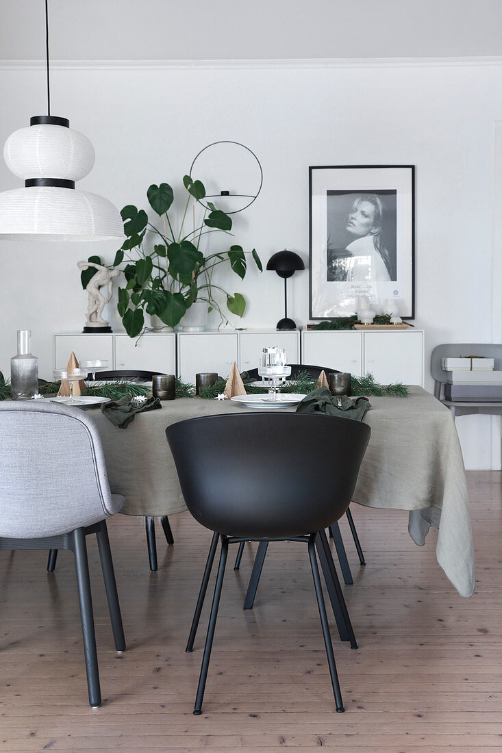 Table set for Christmas with grey tablecloth in front of houseplant n sideboard