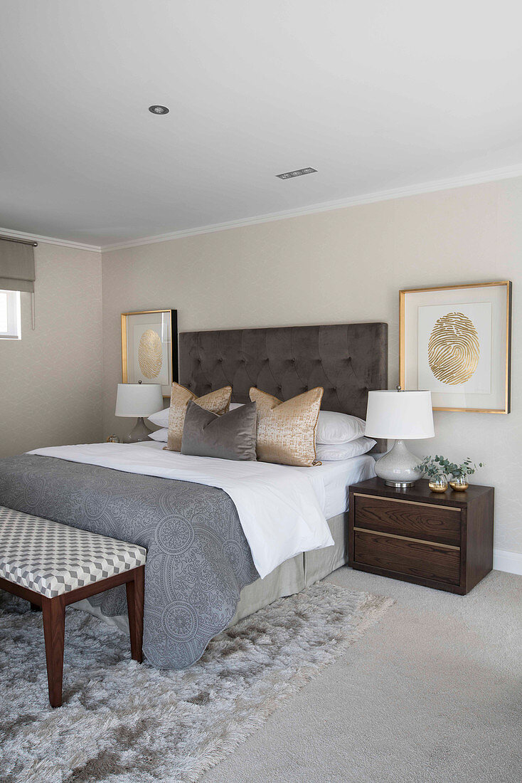 Gilt-framed pictures of fingerprints flanking bed in bedroom