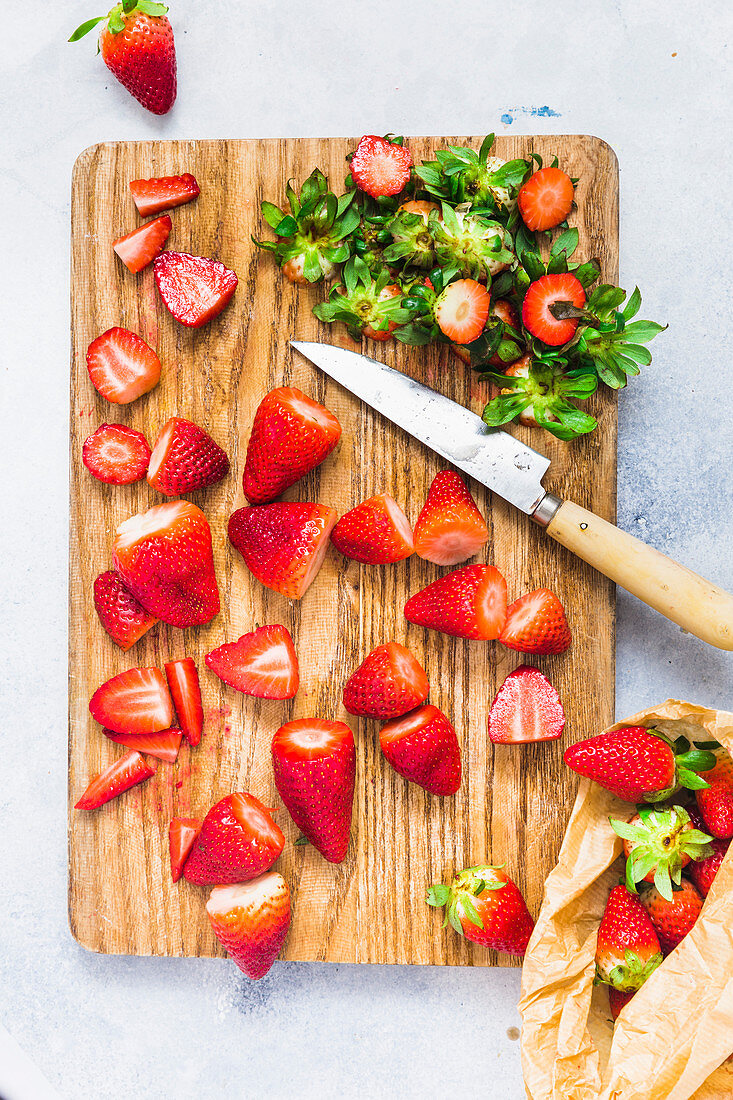 Erdbeeren auf Holzbrett, entstielt und in Stücke geschnitten