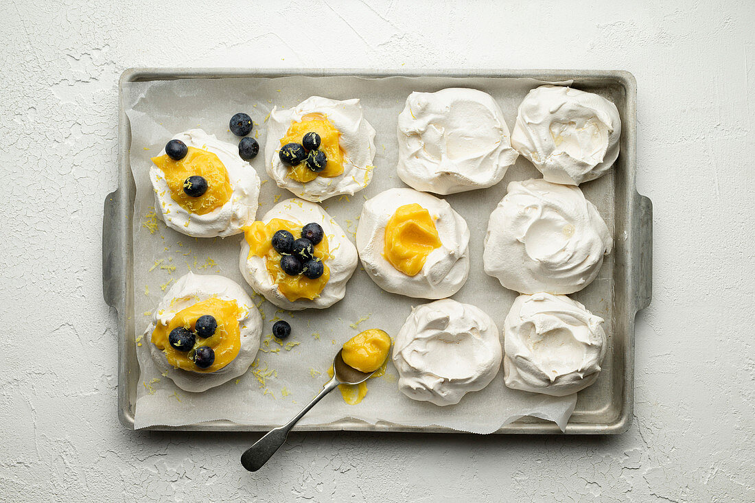 Meringue nests with lemon curd and blueberries on a baking tray