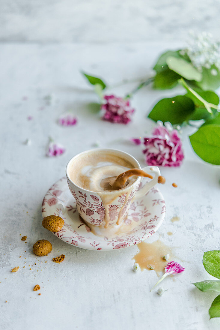 A cup of coffee decorated with milk a foam heart and flowers