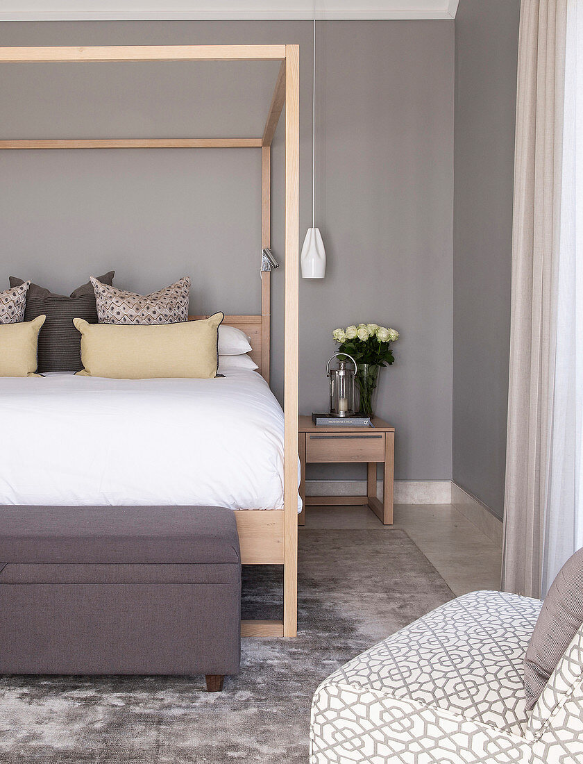 Modern, wooden, four-poster bed in bedroom in shades of grey