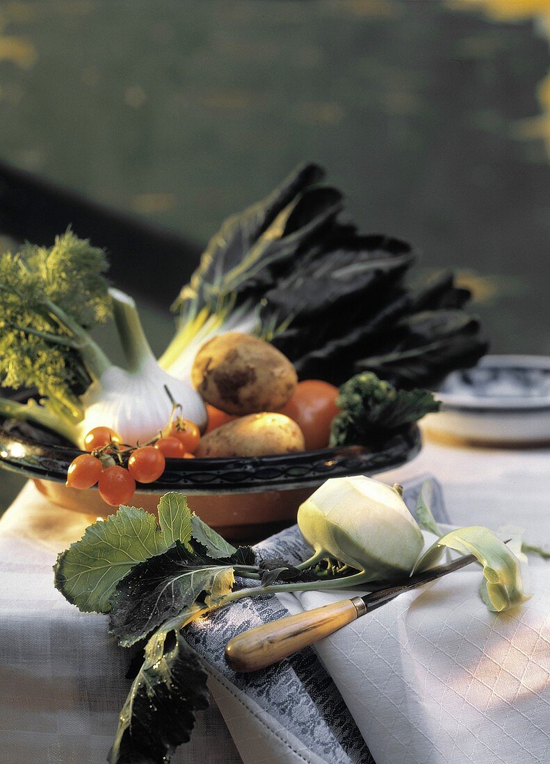 Geschälter Kohlrabi vor einer Schale mit Gemüse auf dem Tisch