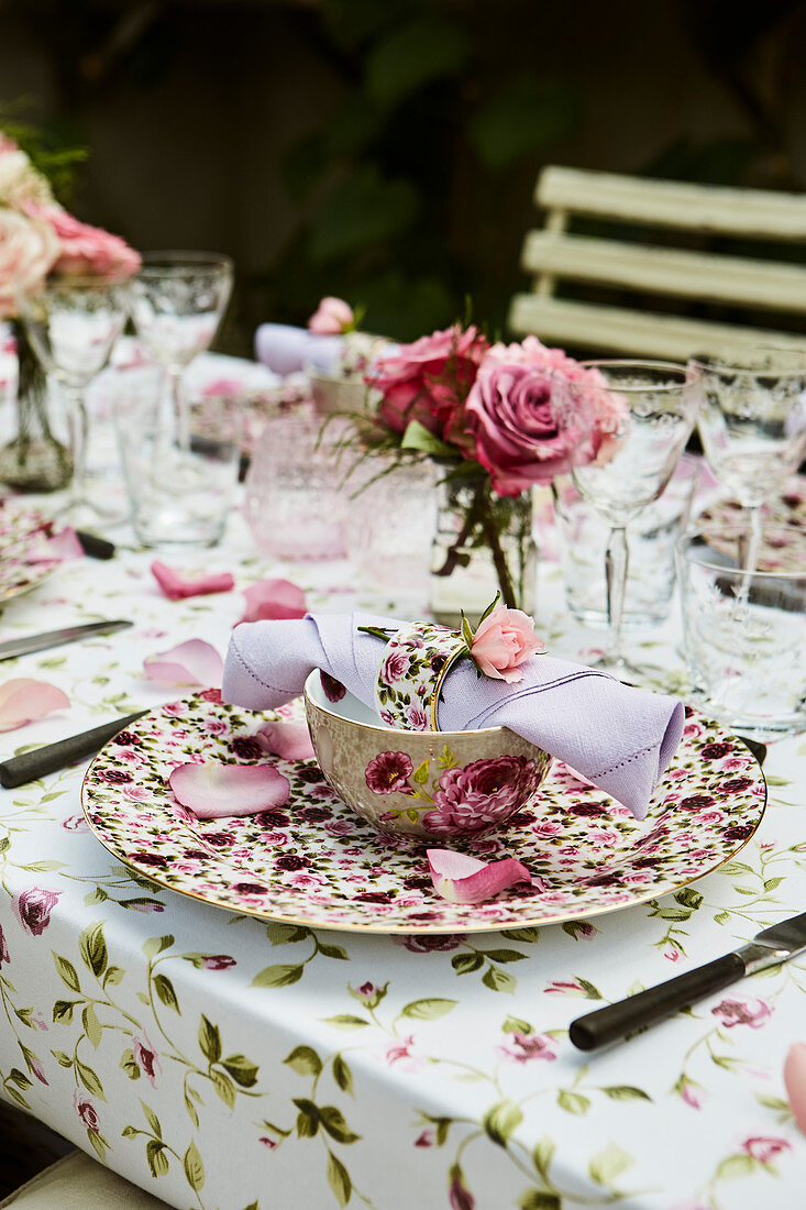 Gedeckter Tisch im Freien mit Rosenblütendeko