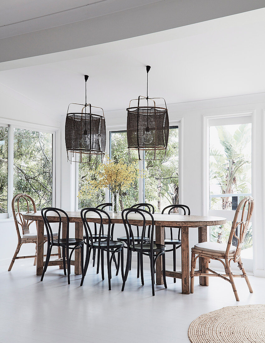 Wooden dining table with bentwood chairs in front of a window, bamboo hanging lamps above