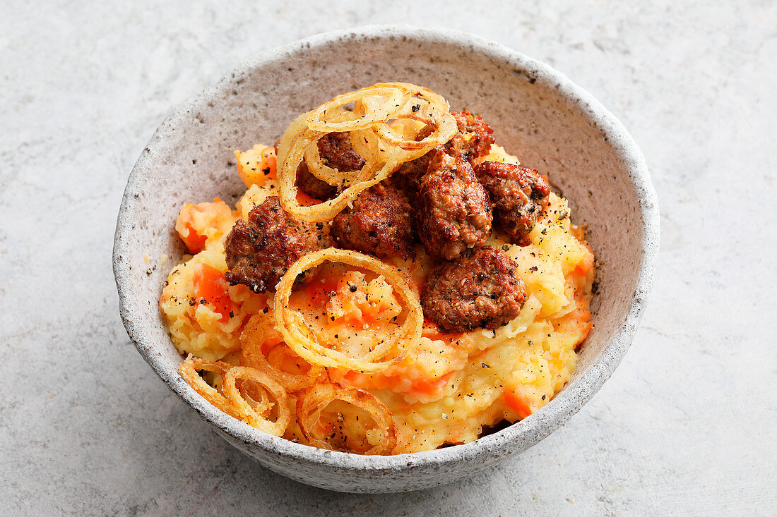 Mashed potatoes and carrots with sausage meat balls and onion rings