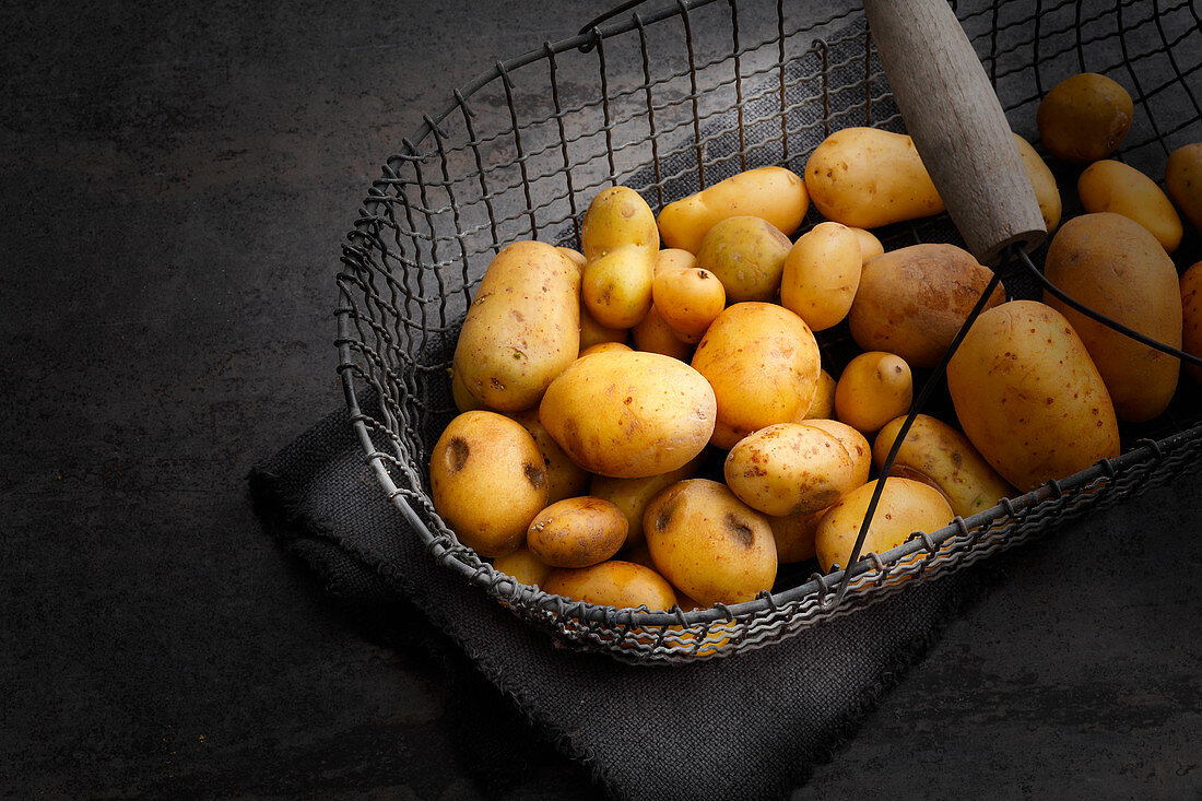 Potatoes in a wire basket being stored in a cool, airy place