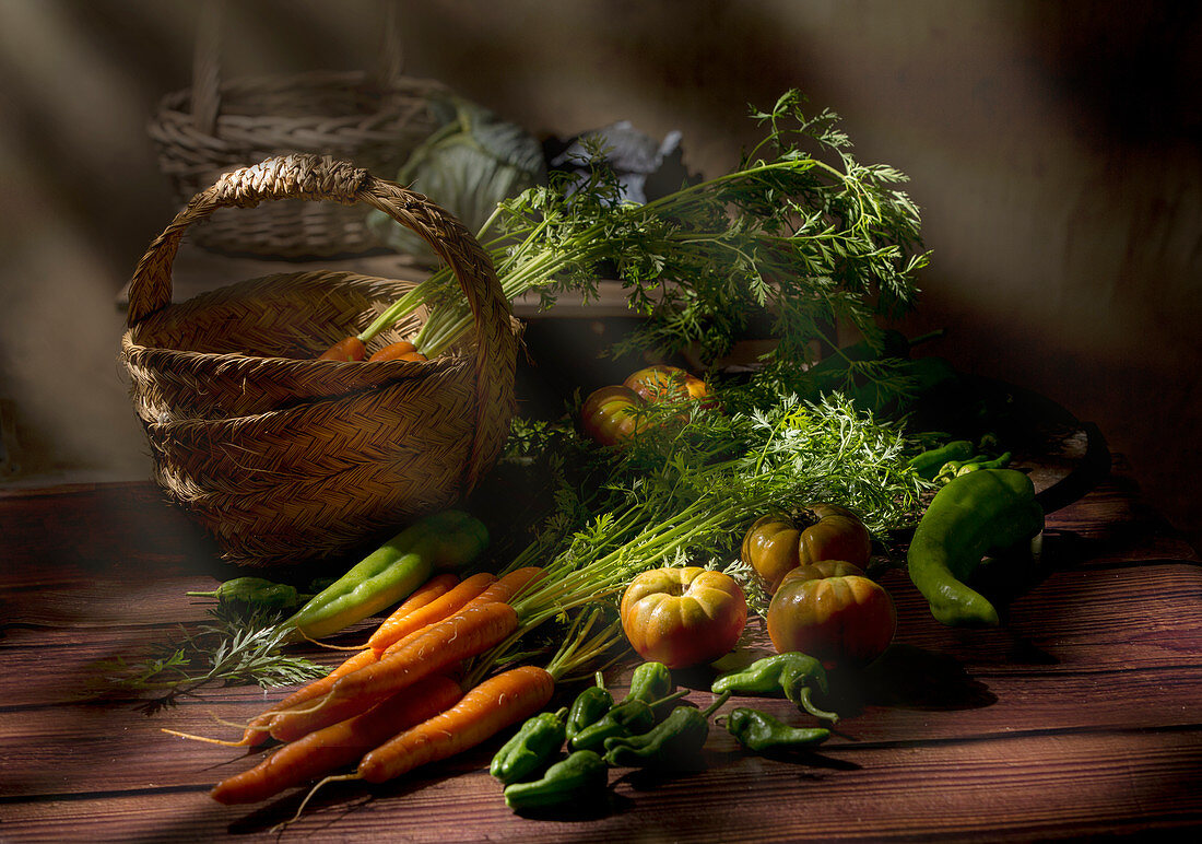 Carrot with lush green stem tomatoes pepper on round tray and cabbage in baskets on wooden table