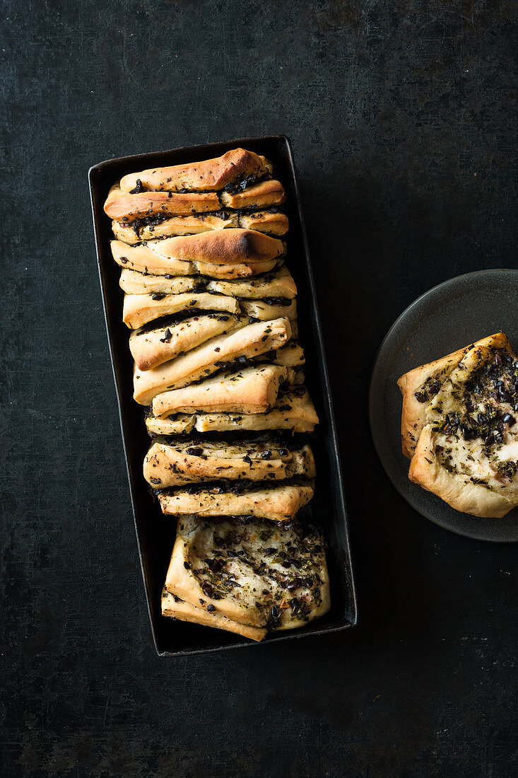 Olive pull-apart bread in a loaf tin and on a plate