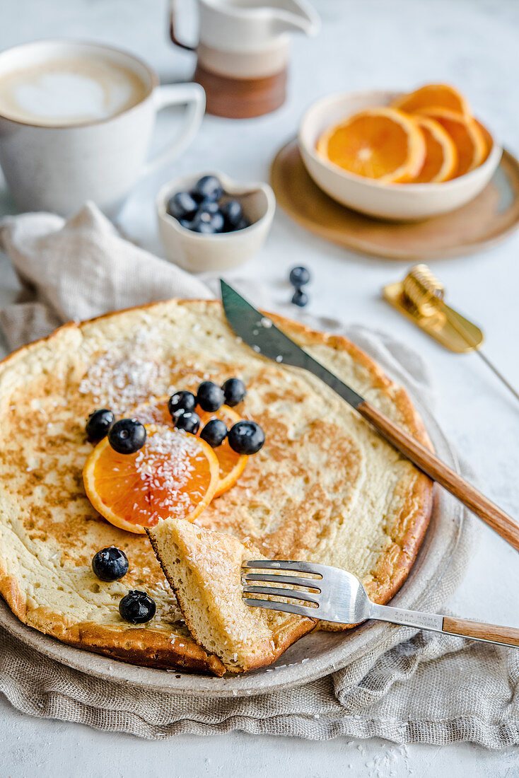 Fluffy omelette with blueberries and oranges served with coffee