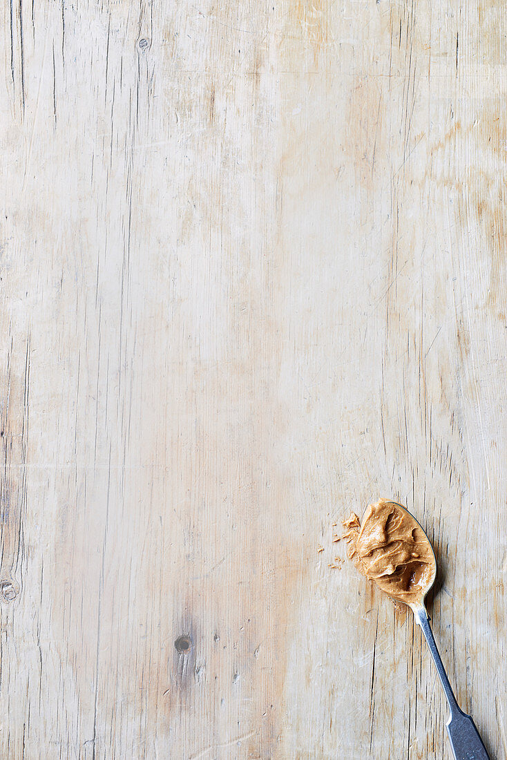 Ein Löffel Erdnussbutter auf Holzuntergrund