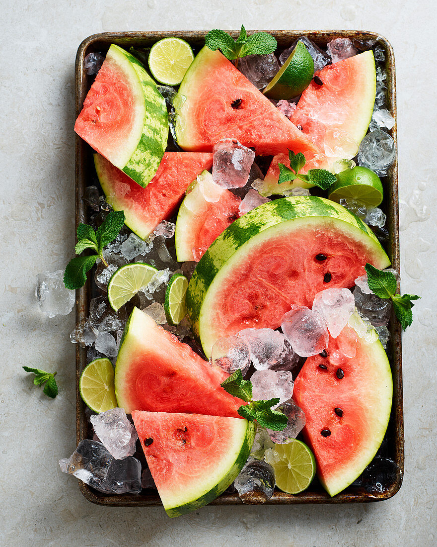 Watermelon slices with ice cubes, limes and mint