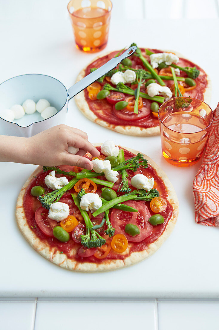 Regenbogen-Pizza mit Gemüse und Mozzarella belegen