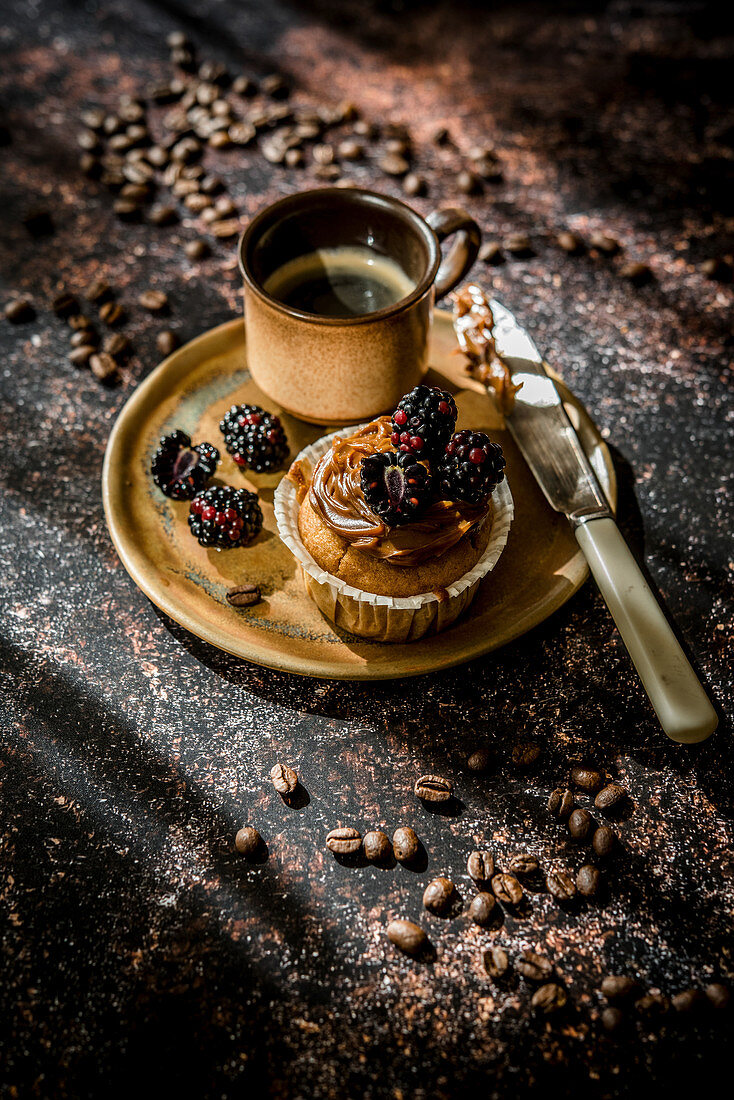 Cupcake mit Karamellcreme und Brombeeren dazu eine Tasse Kaffee