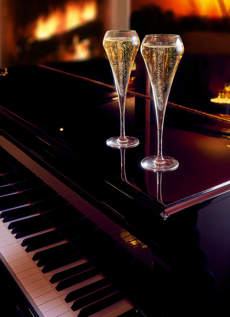 Two champagne glasses on a piano