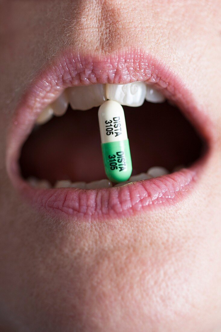 Close-up of Prozac capsule clenched between teeth