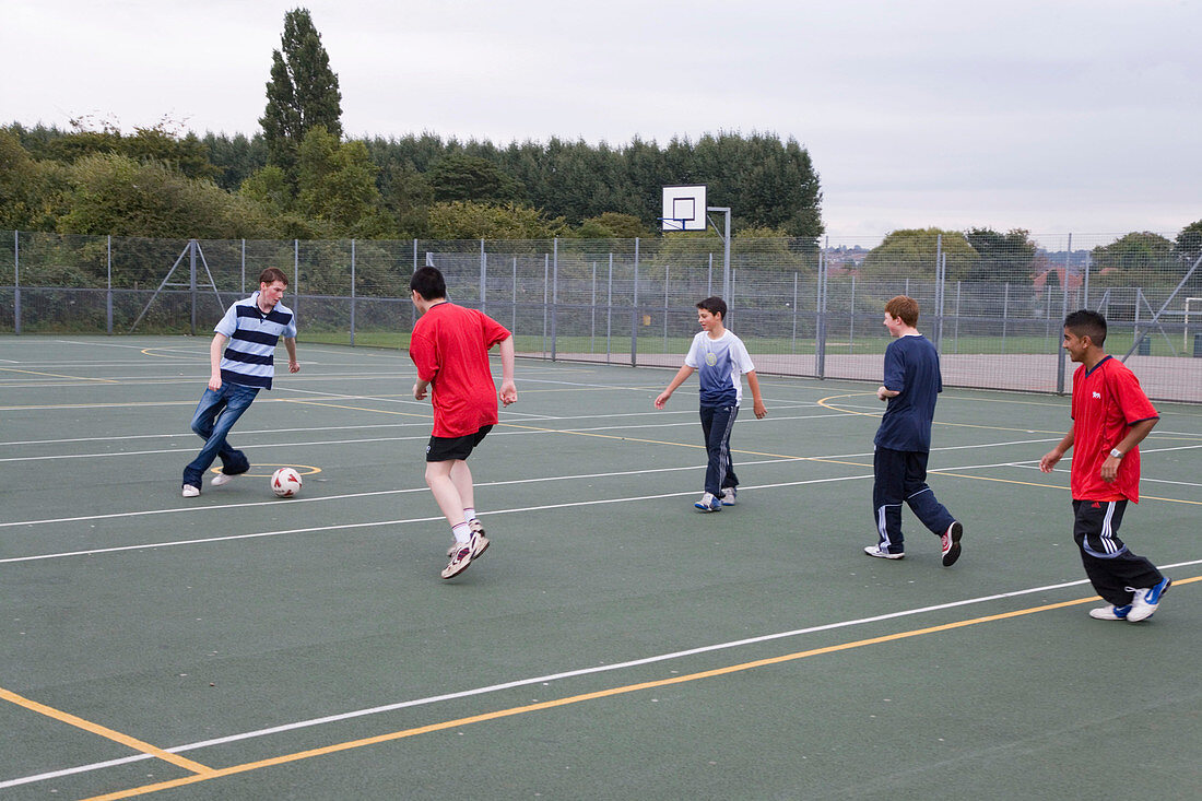 Group of teenage boys having a kick about with a football