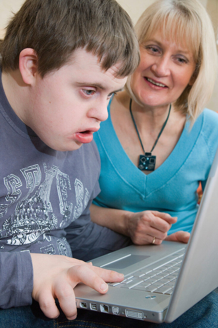 Mother and teenage son with Down Syndrome using a laptop