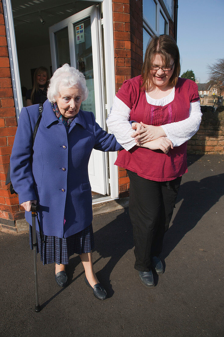Carer helping old woman walking