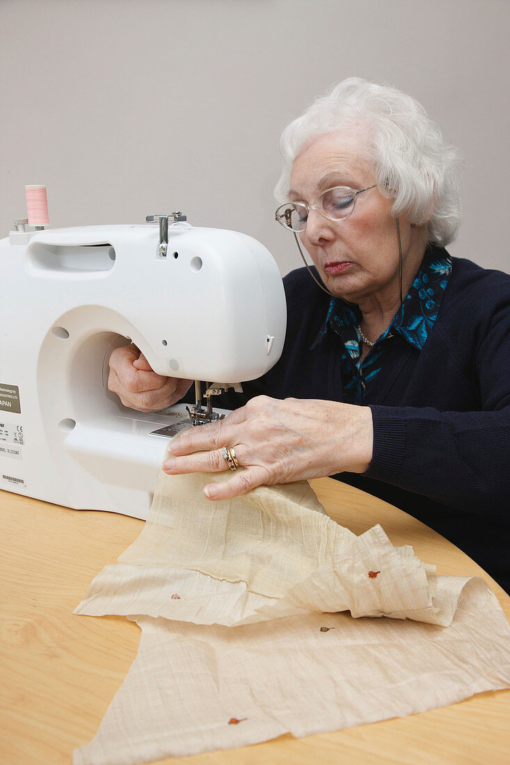 Elderly woman using sewing machine
