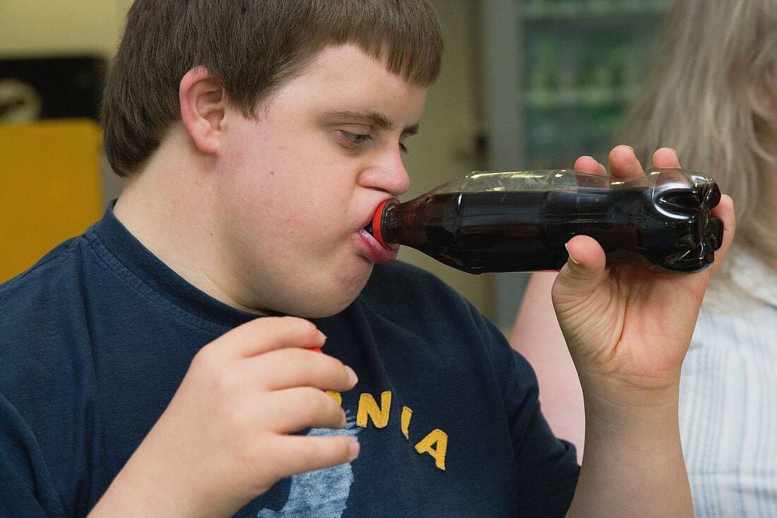Teenage boy with Down Syndrome drinking a bottle of cola