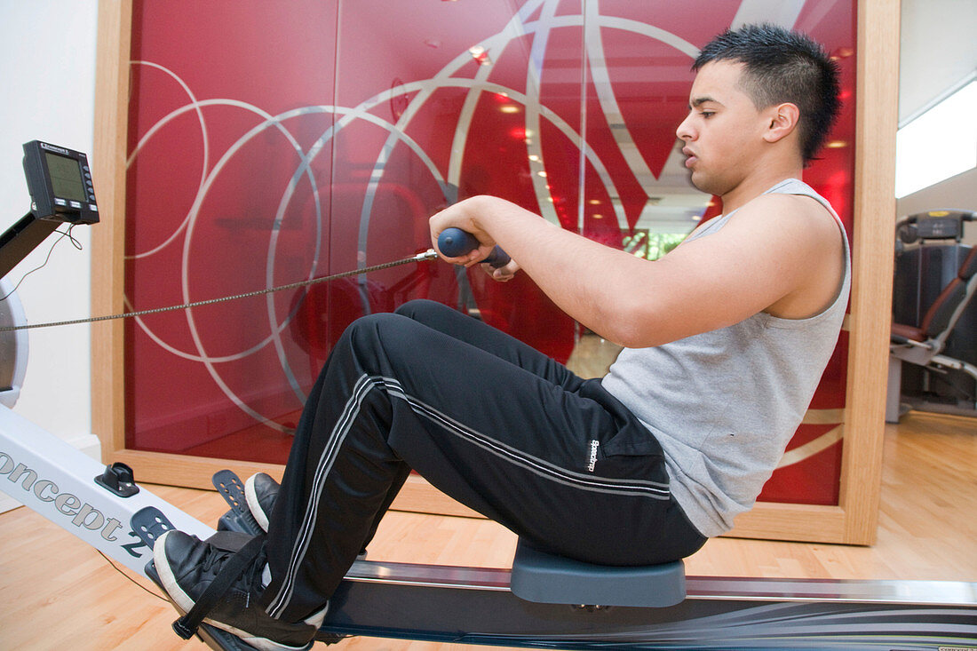 Young man using a rowing machine at gym