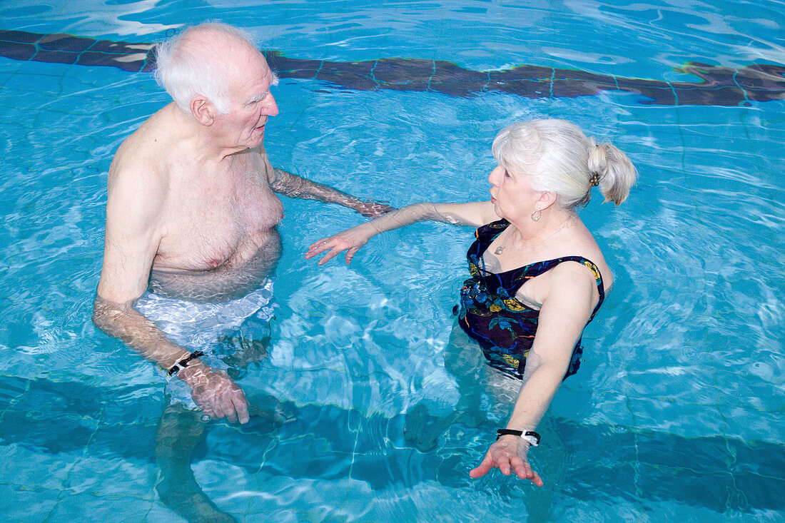 Two older people having a chat in a swimming pool
