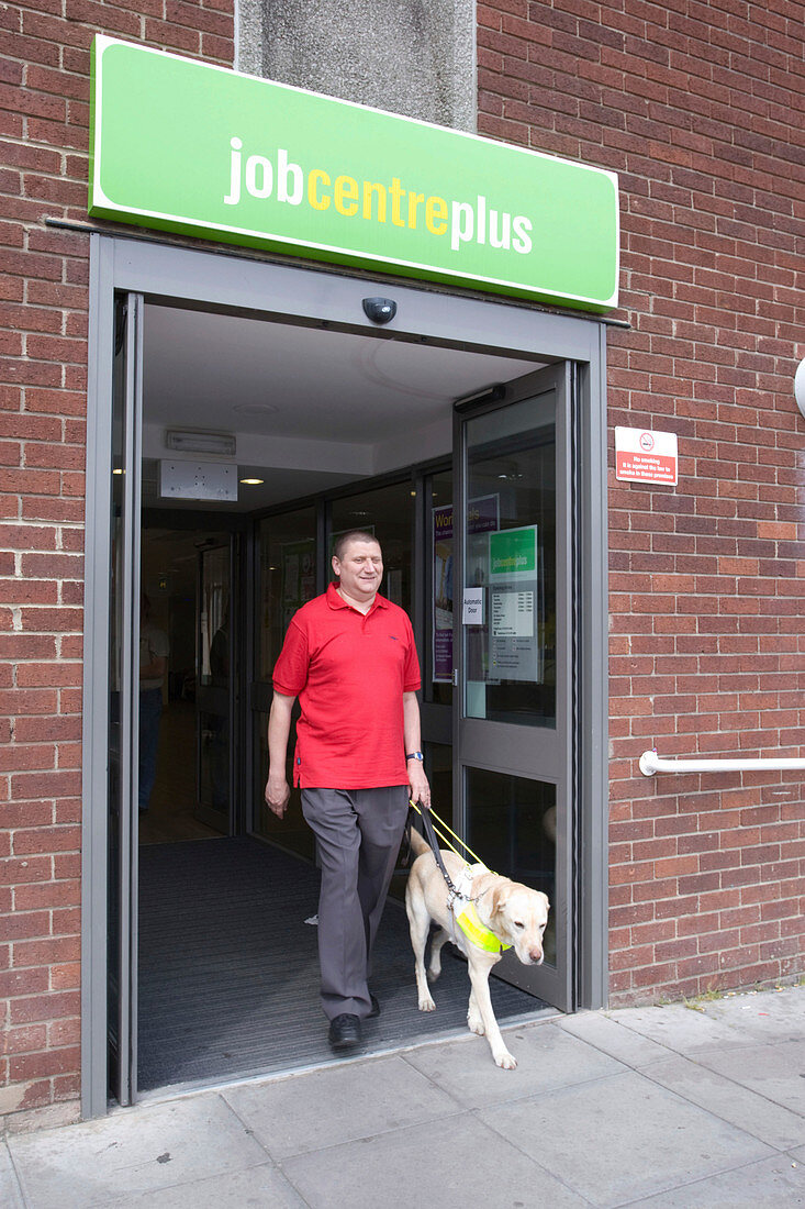 Vision impaired man and guide dog leaving job centre