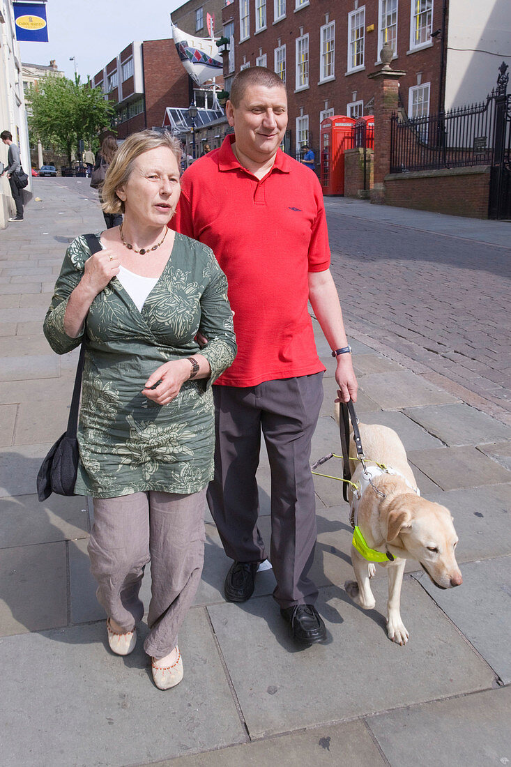 Vision impaired man with guide dog and sighted guide