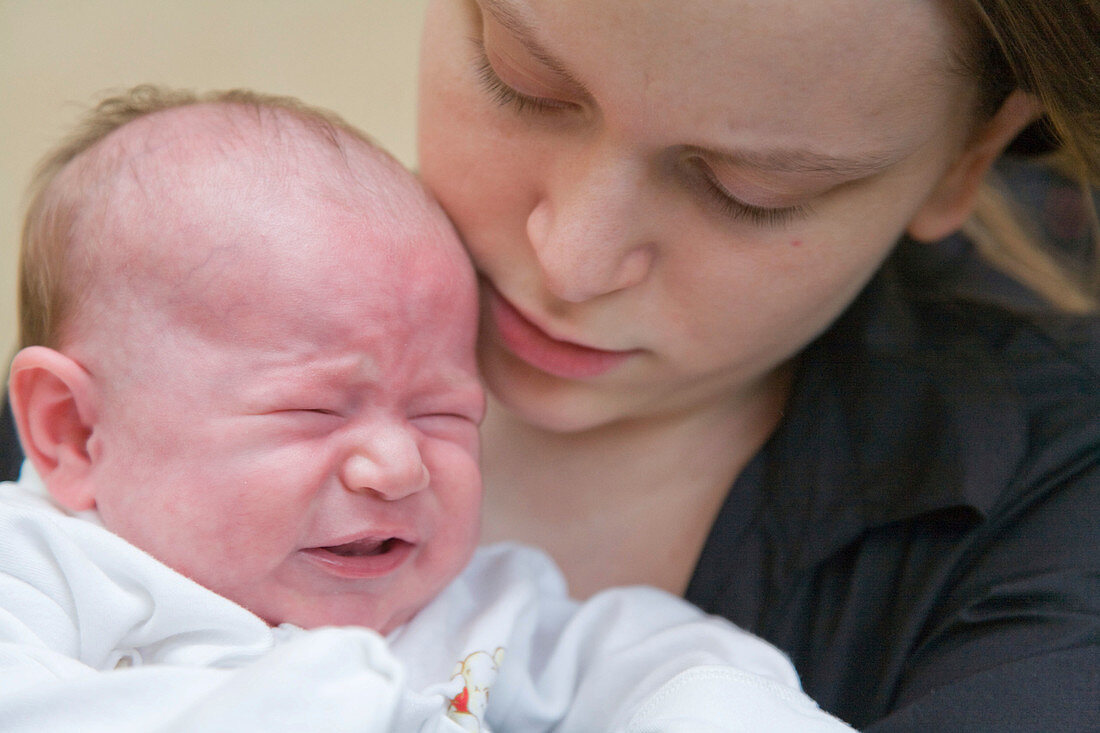 Young mother holding her crying five week old baby