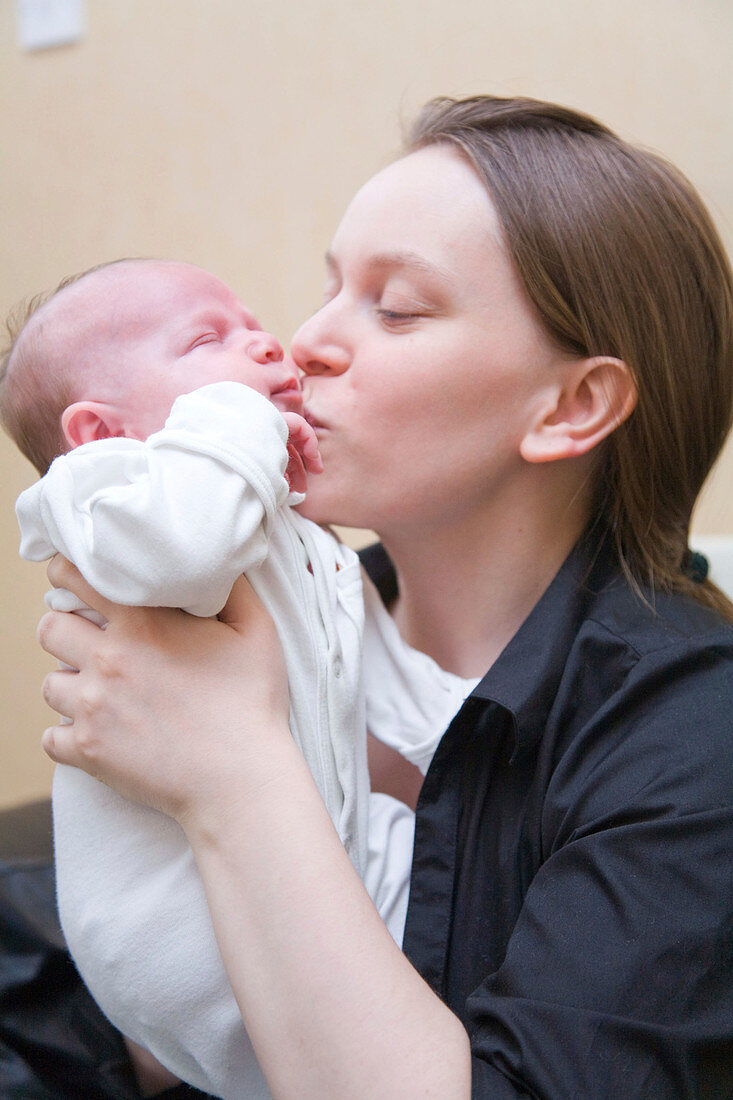 Young mother kissing her five week old baby