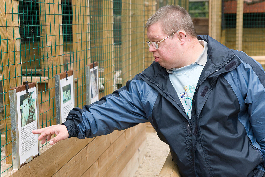 Man with learning disabilities reading sign on a bird cage