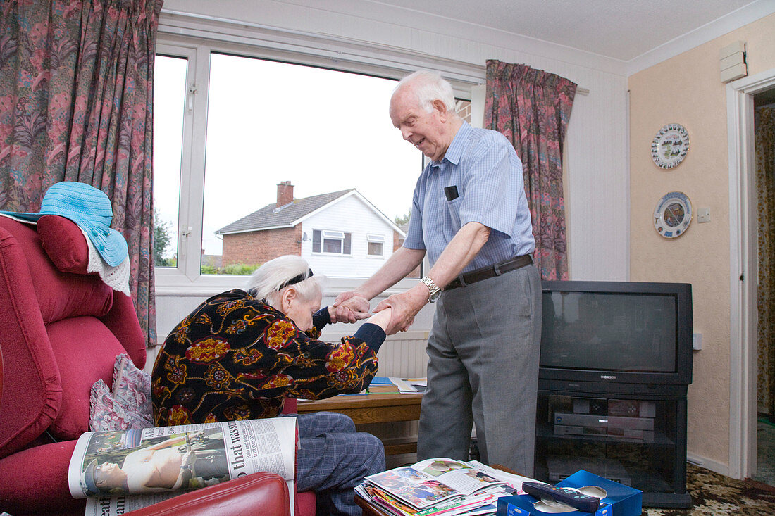 Elderly carer helping his wife with Alzheimer's disease