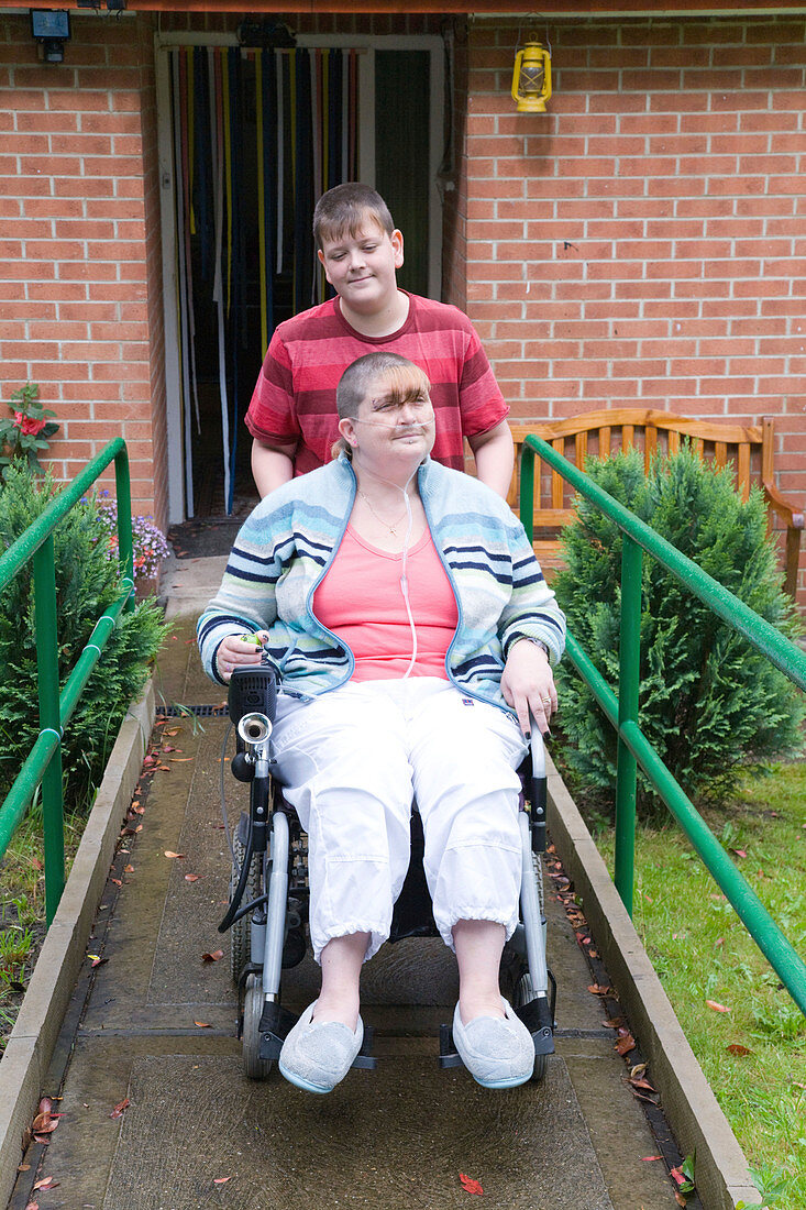 Young carer pushing his mother in a wheelchair